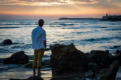 Rear view of man looking at sea against sky