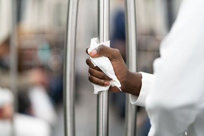 Closeup of black man hand holding handrail in public transport or subway through a napkin.