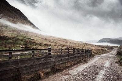 Scenic view of road by mountains against sky