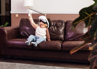 Full length of boy relaxing on sofa at home