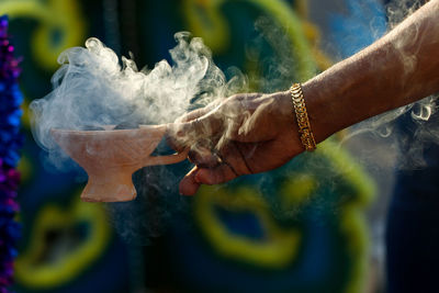 Cropped hand of man holding religious offering