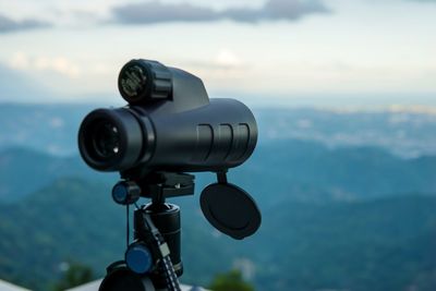 Close-up of binocular on landscape against sky