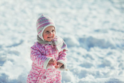 Smiling girl wearing hat against snow during winter