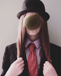 Woman with apple in front of face against gray background