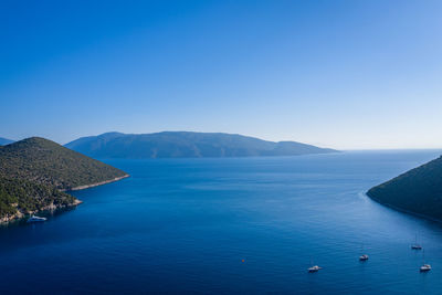 Scenic view of sea and mountains against clear blue sky