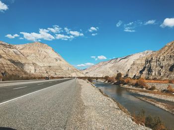 Road by mountains against sky