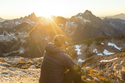 Rear view of active man enjoying scenic mountain view at sunset.