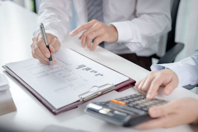 Midsection of real estate agent giving key to customer on table