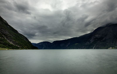 Scenic view of lake and mountains against storm clouds