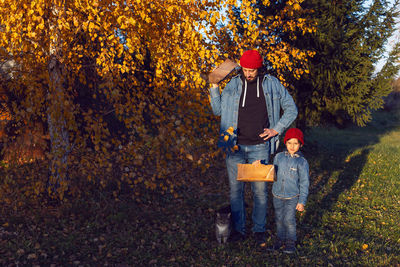 Father and son carry firewood outside in the evening in autumn at sunset in nature