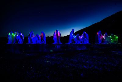 Illuminated sculptures and lights against blue sky at night