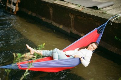 High angle view of woman lying in hammock over lake