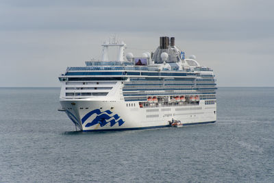 Cruise ship at anchor while being loaded via a small passenger boat