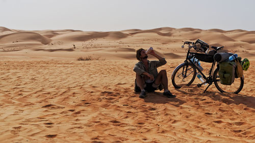 People on sand dune in desert against sky