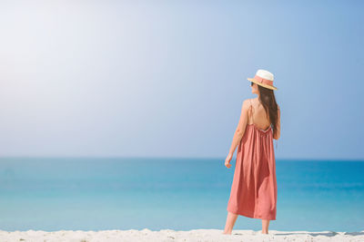 Rear view of woman standing by sea against sky