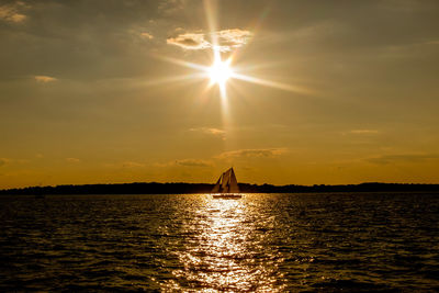 Silhouette of sailboat in sea during sunset