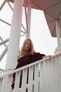 Low angle portrait of woman against railing