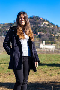 Portrait of young woman standing on land against clear blue sky