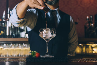 Midsection of man pouring wine in glass