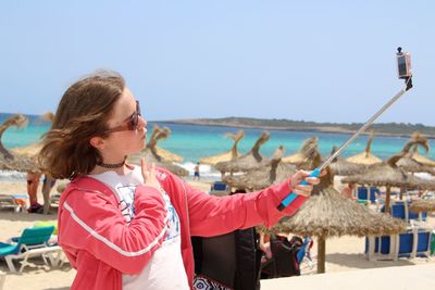 Girl taking selfie at beach against clear sky