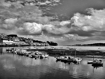 Boats in sea against cloudy sky