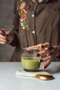 Midsection of woman holding drink on table