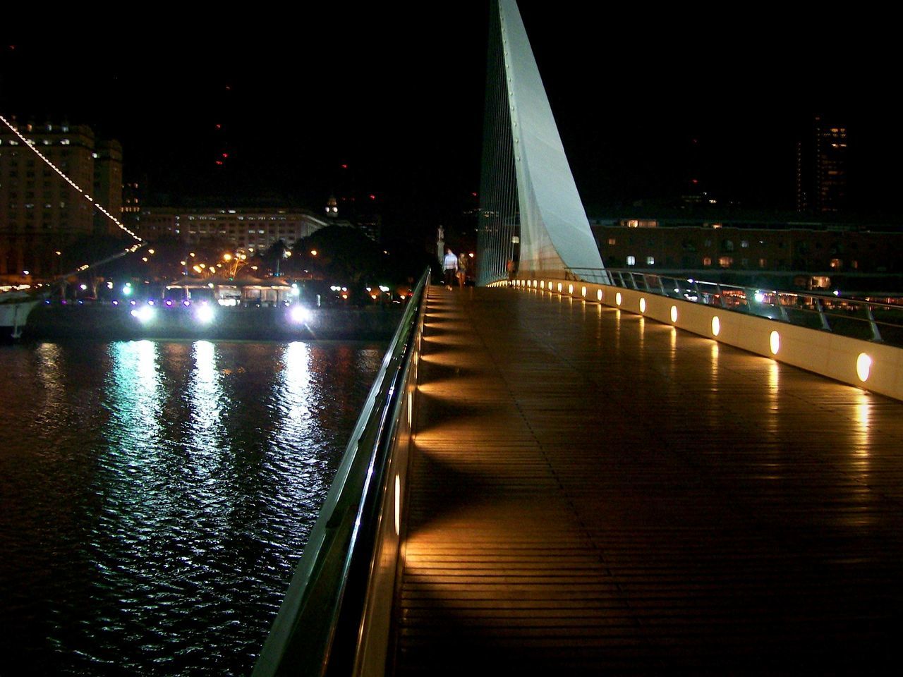 illuminated, night, architecture, built structure, city, the way forward, building exterior, street light, water, railing, transportation, reflection, bridge - man made structure, lighting equipment, sky, diminishing perspective, river, connection, modern, outdoors