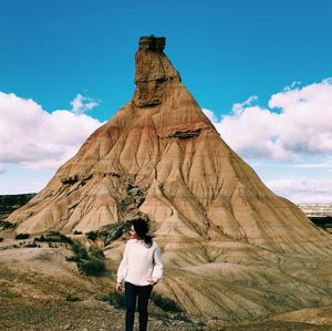 Young woman looking away while standing against rock formation