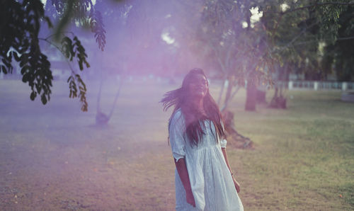 Woman standing by tree on field
