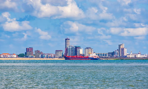 Sea by buildings against sky in city