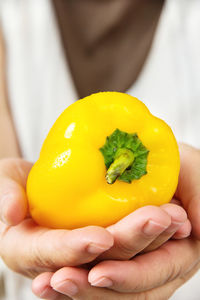 Cropped image of person holding yellow bell pepper