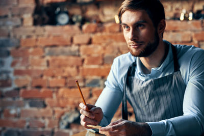 Portrait of young man sitting against wall