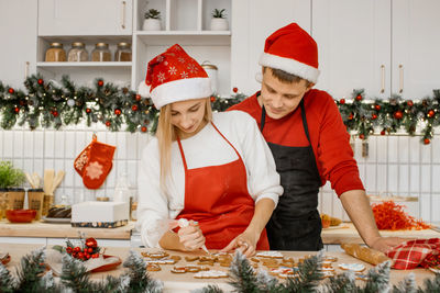 Woman and her husband are in process of decorating the christmas homemade gingerbread cookies