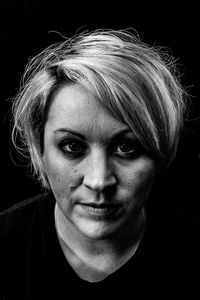 Close-up portrait of woman against black background