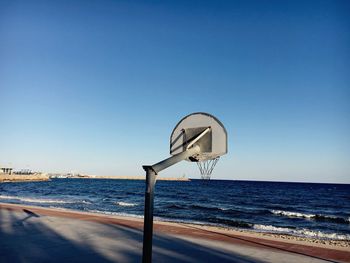 Basketball hoop on sea against clear sky