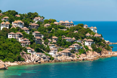 Buildings by sea against blue sky