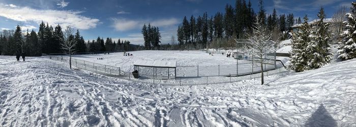 Panoramic view of snow covered field against sky