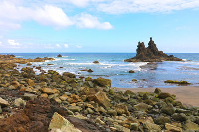 Rocks on sea shore against sky