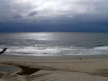 Scenic view of beach against cloudy sky