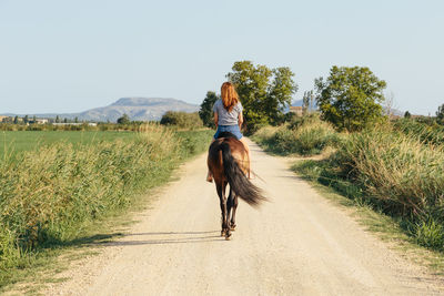 Beautiful woman riding along a country road on a sunny afternoon