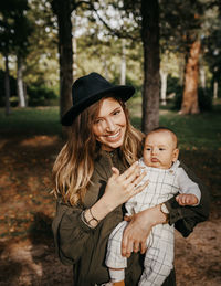 Portrait of a smiling young woman with hat on tree