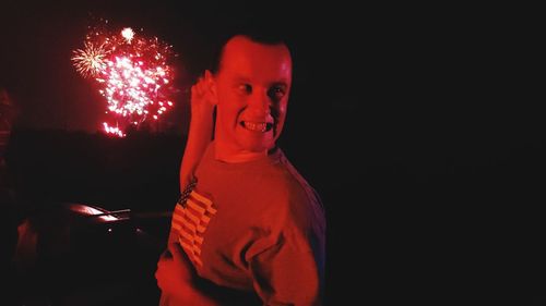 Portrait of smiling woman standing against black background