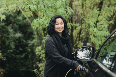 Portrait of smiling woman standing against trees