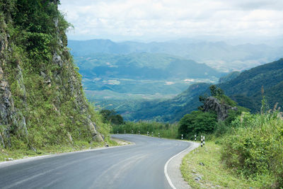 Scenic view of road by mountains against sky