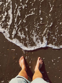 Low section of man standing on beach