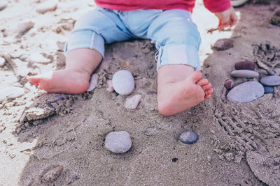 Low section of child playing on sand at beach
