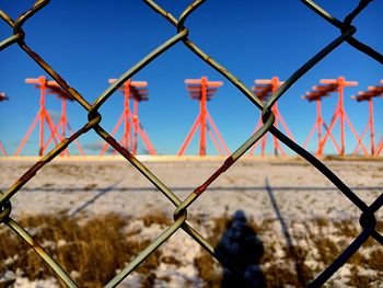 Close-up of red structure seen through chainlink fence against clear sky