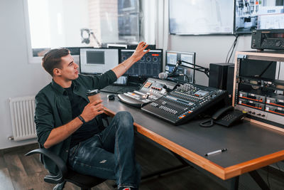 Young man is indoors in the radio studio is busy by broadcast.