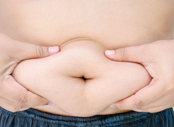 Midsection of man touching belly