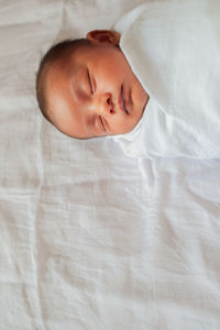 High angle view of boy sleeping on bed